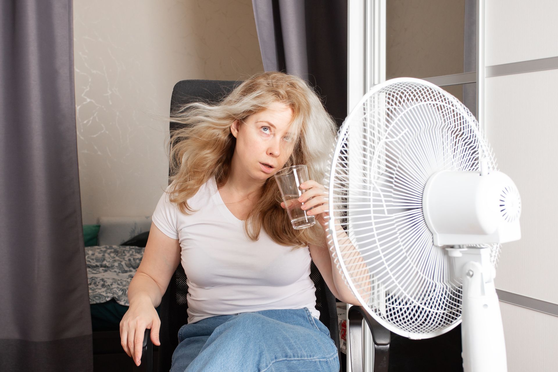 Homeowner feeling uncomfortable in a warm room despite the air conditioner running.