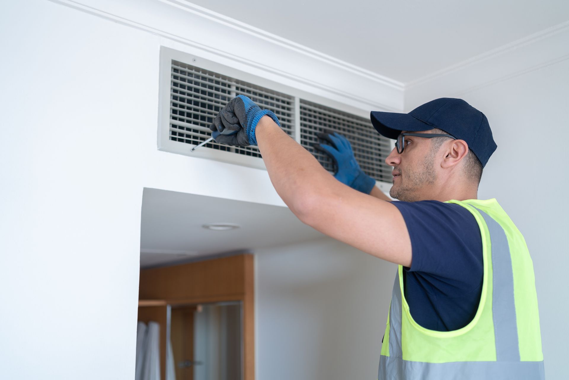 HVAC technician cleaning indoor air vent to improve indoor air quality during allergy season.