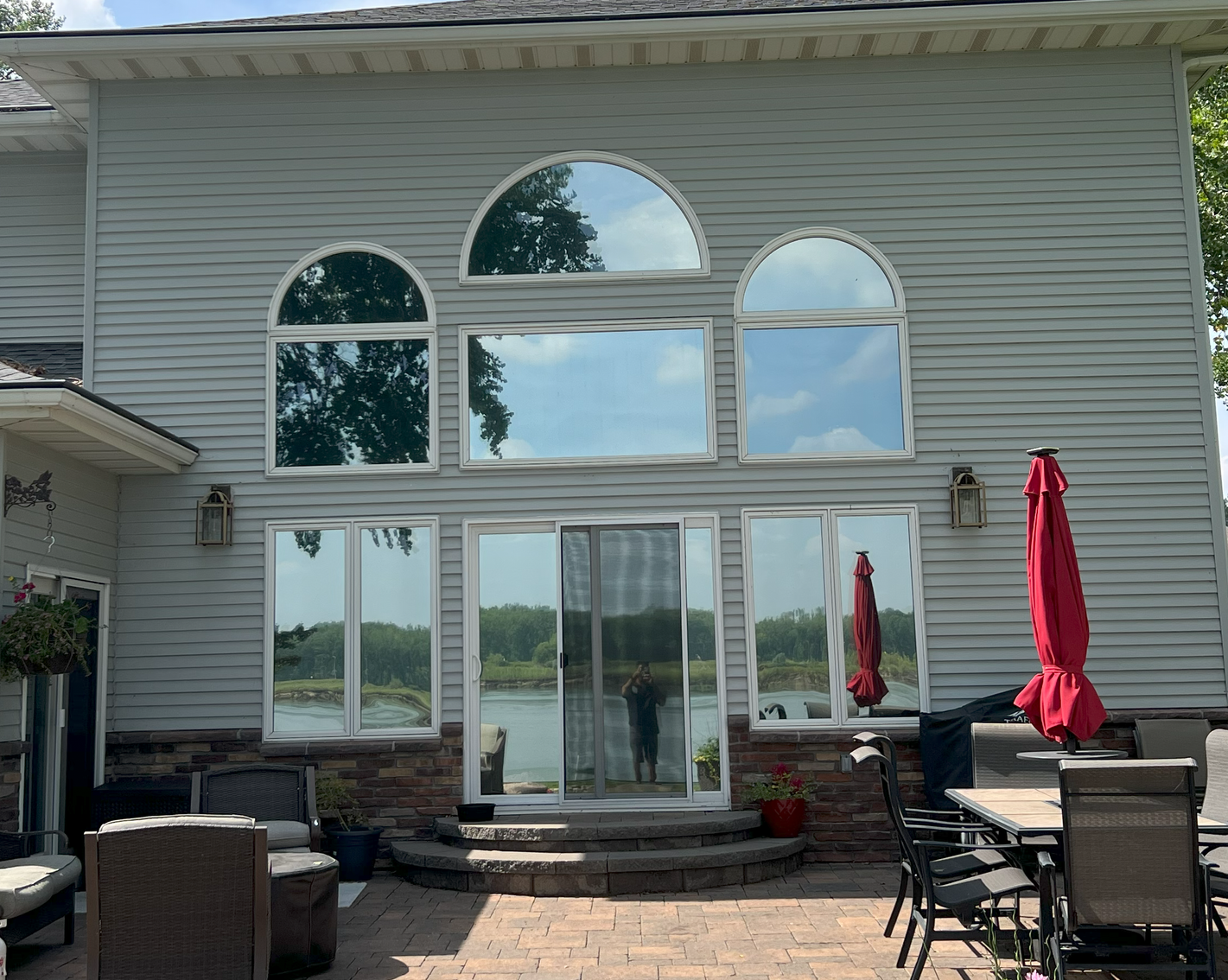 A house with a lot of windows and a patio with a table and chairs.