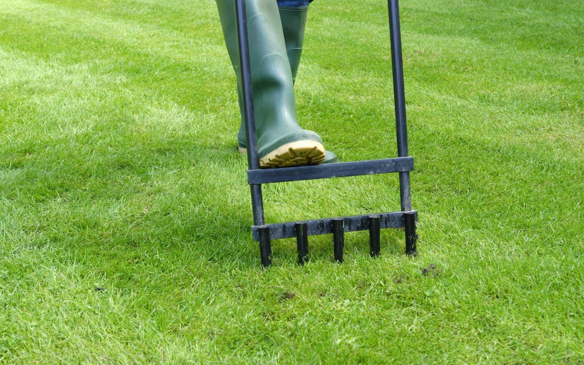 a manual lawn operator is being used to perform soil aeration