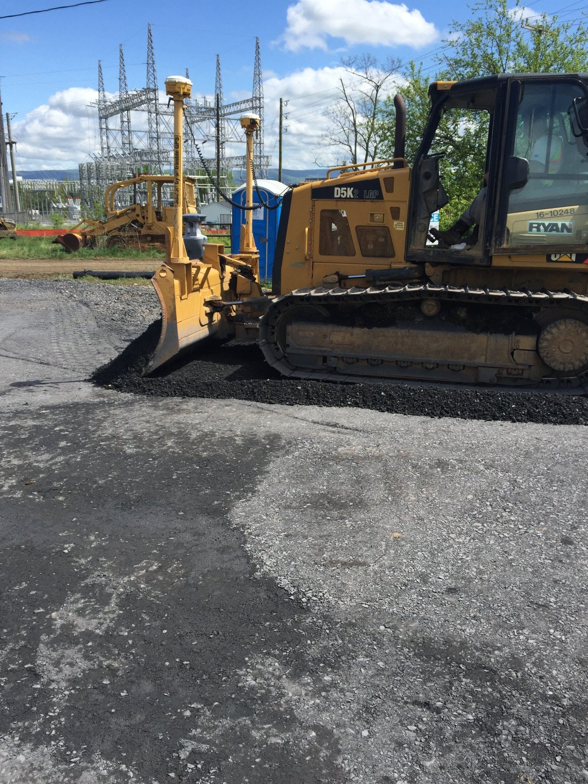 A yellow bulldozer is parked in a gravel lot