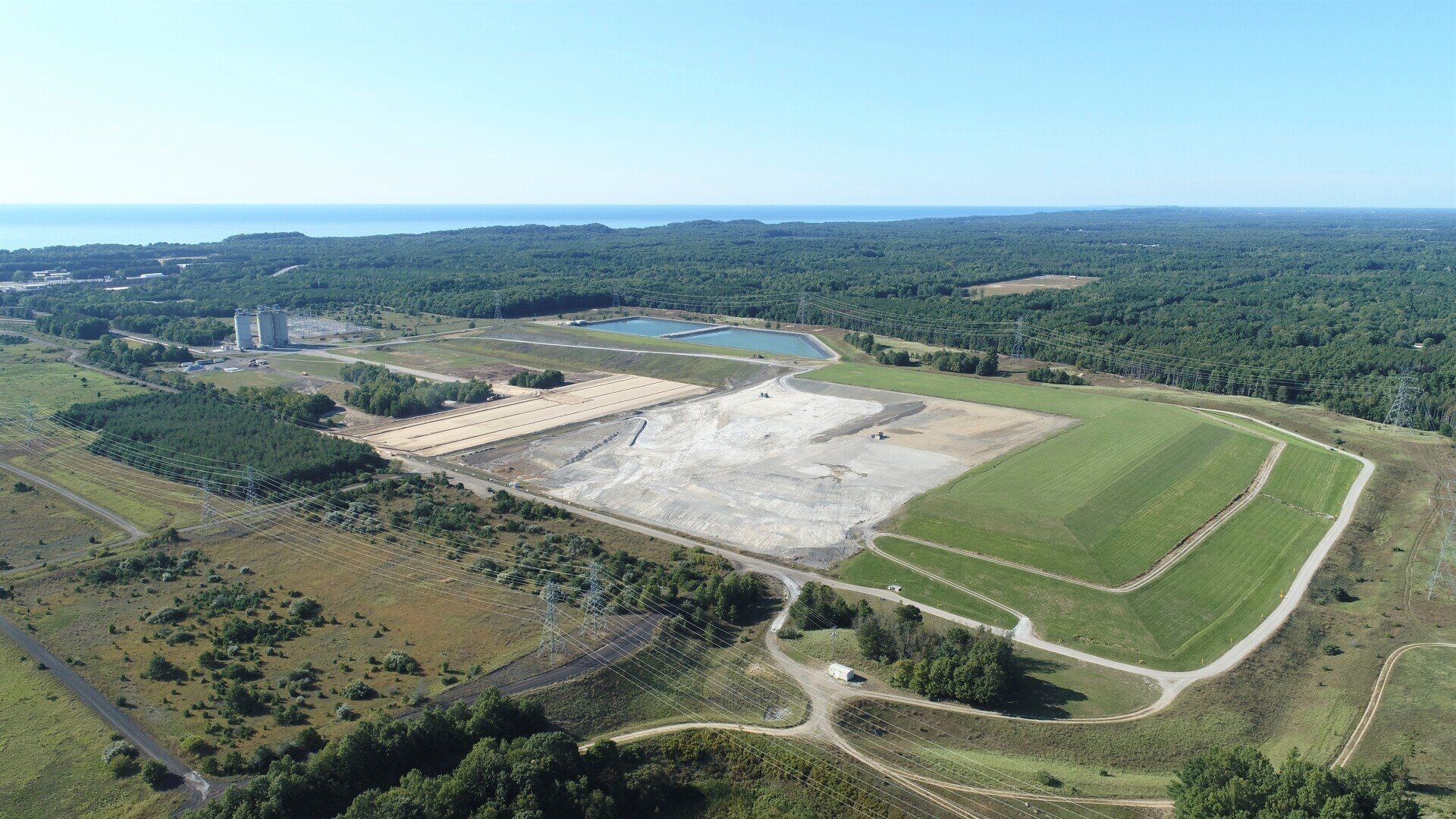 An aerial view of a large field surrounded by trees and a body of water.