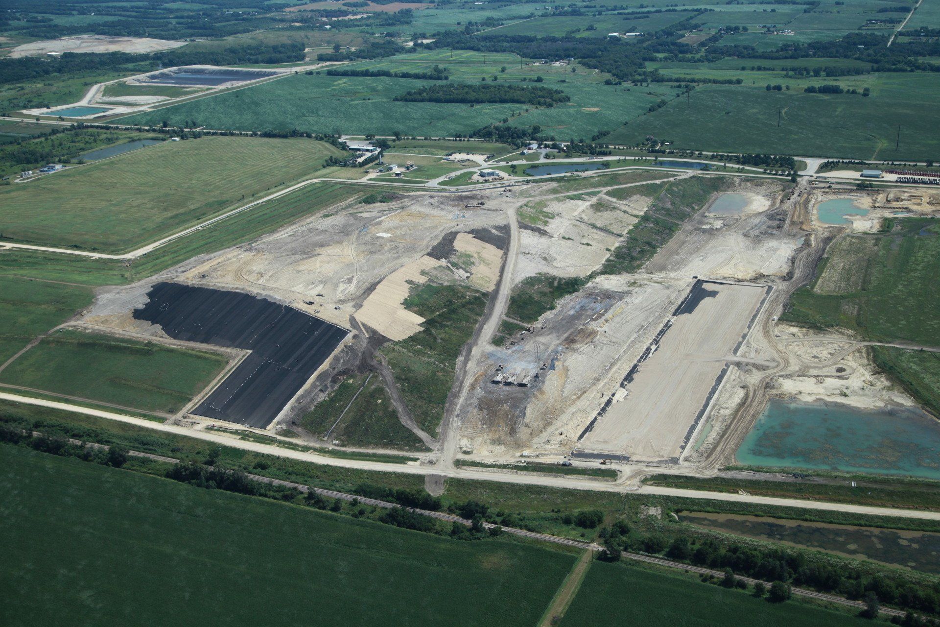 An aerial view of a construction site in the middle of a lush green field