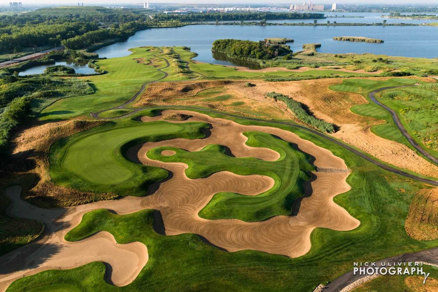 An aerial view of a golf course with a lake in the background.