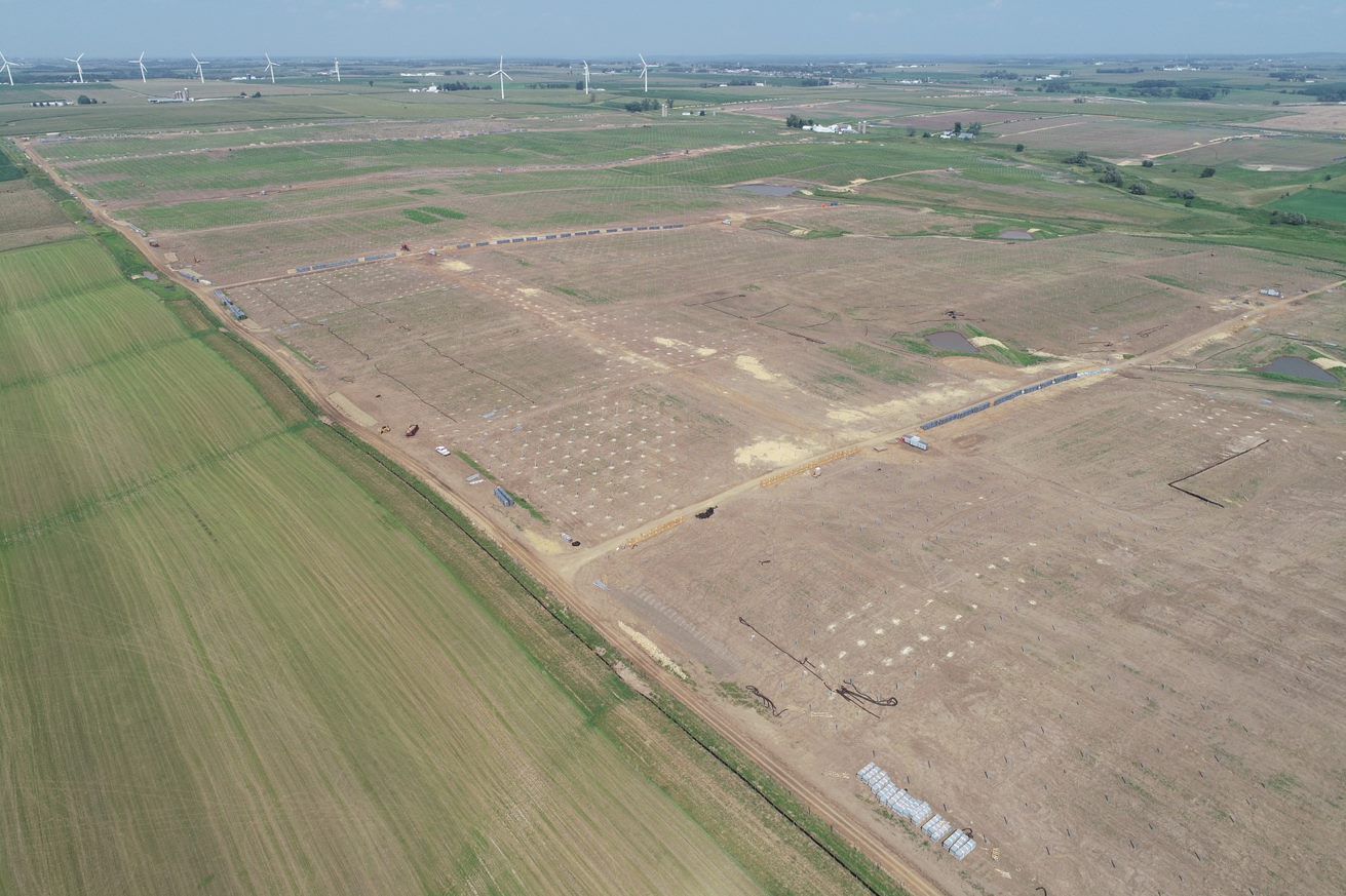 An aerial view of a large field with a dirt road going through it.