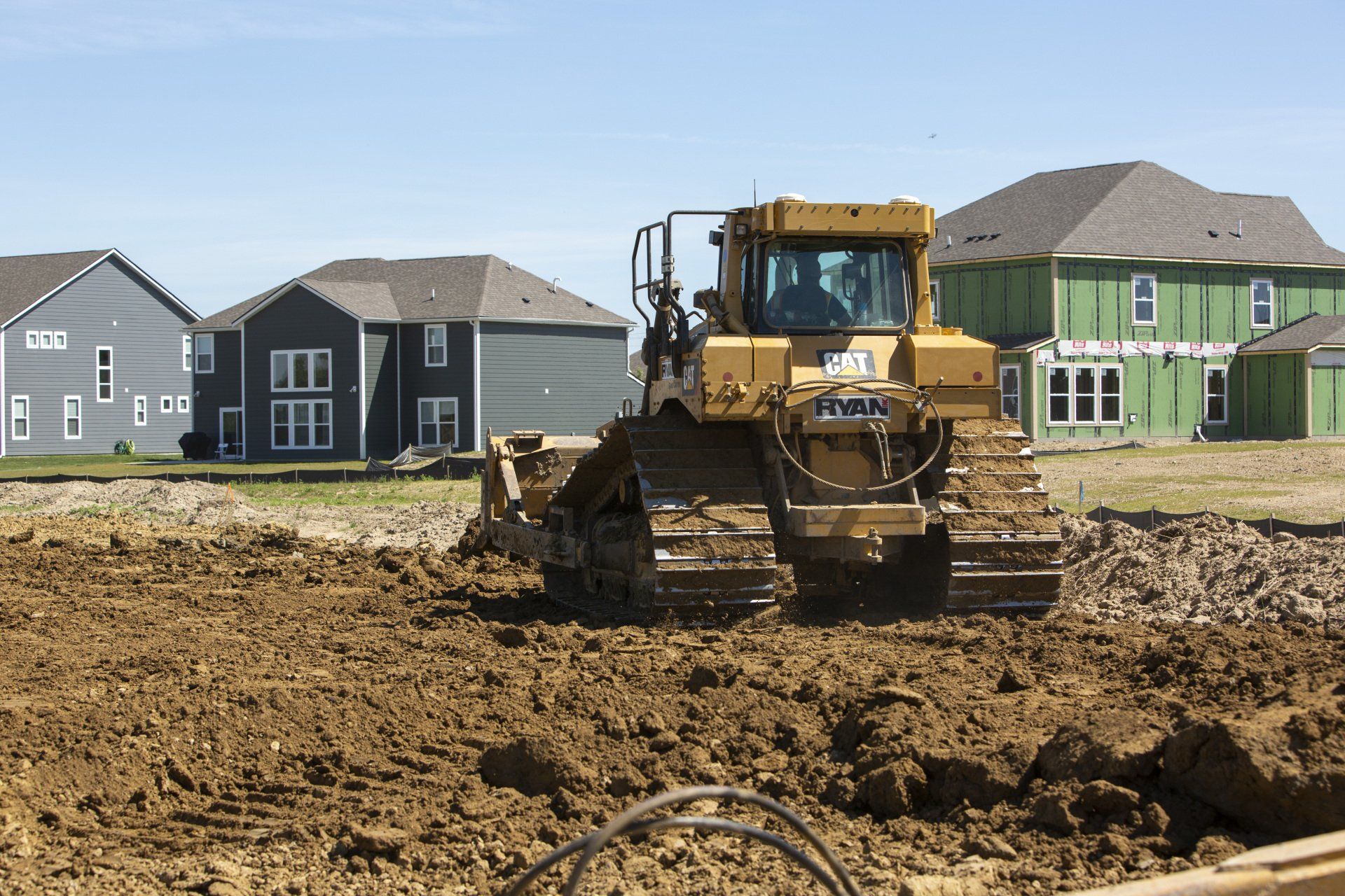 A bulldozer is moving dirt in front of a row of houses