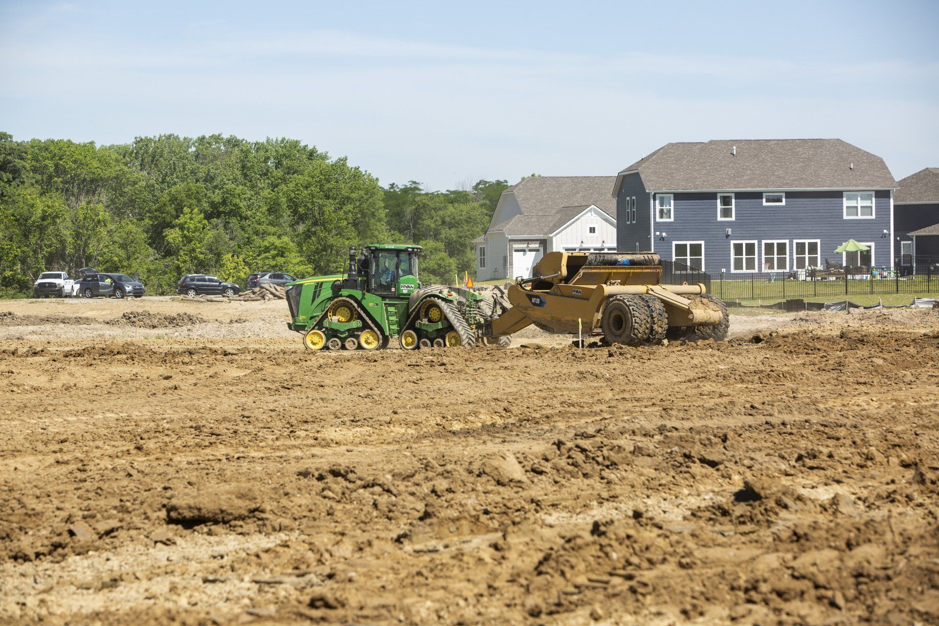 A tractor and bulldozer are working on a dirt field.