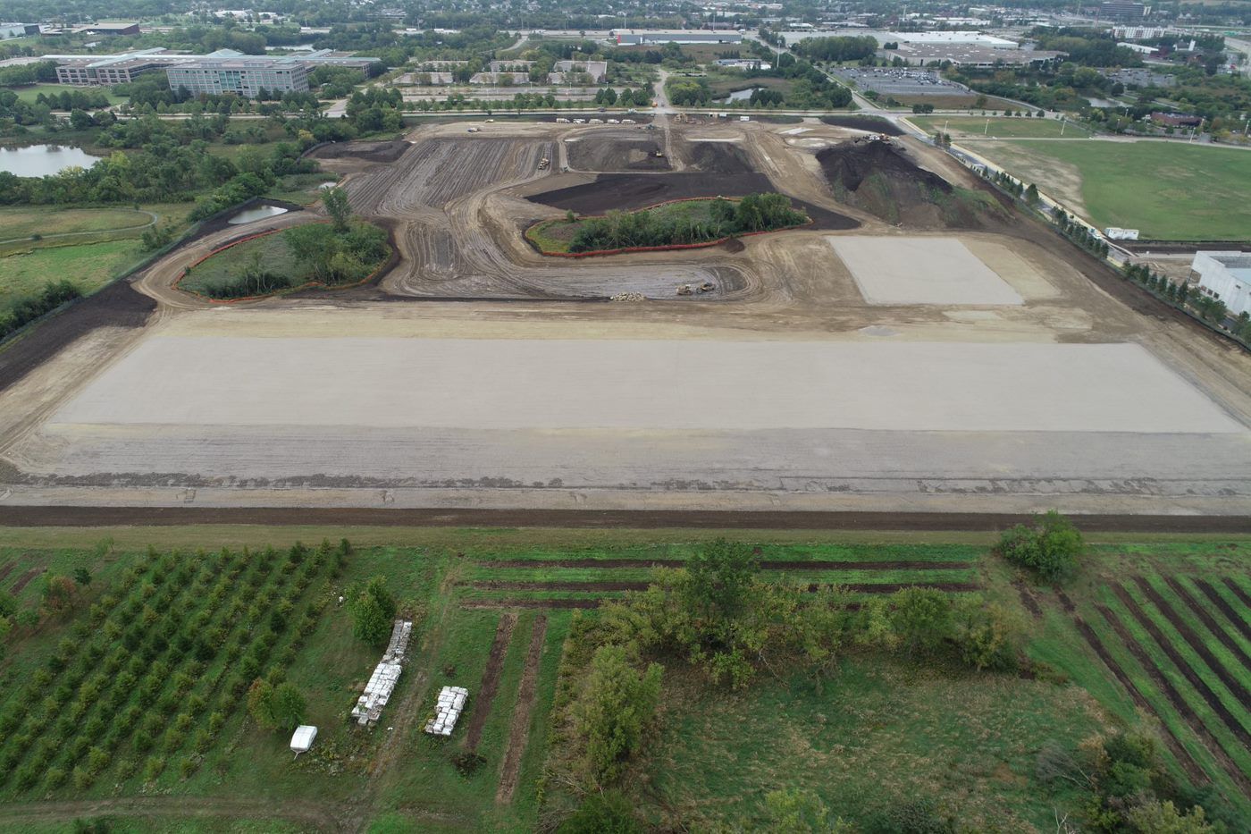 An aerial view of a large dirt field surrounded by trees.