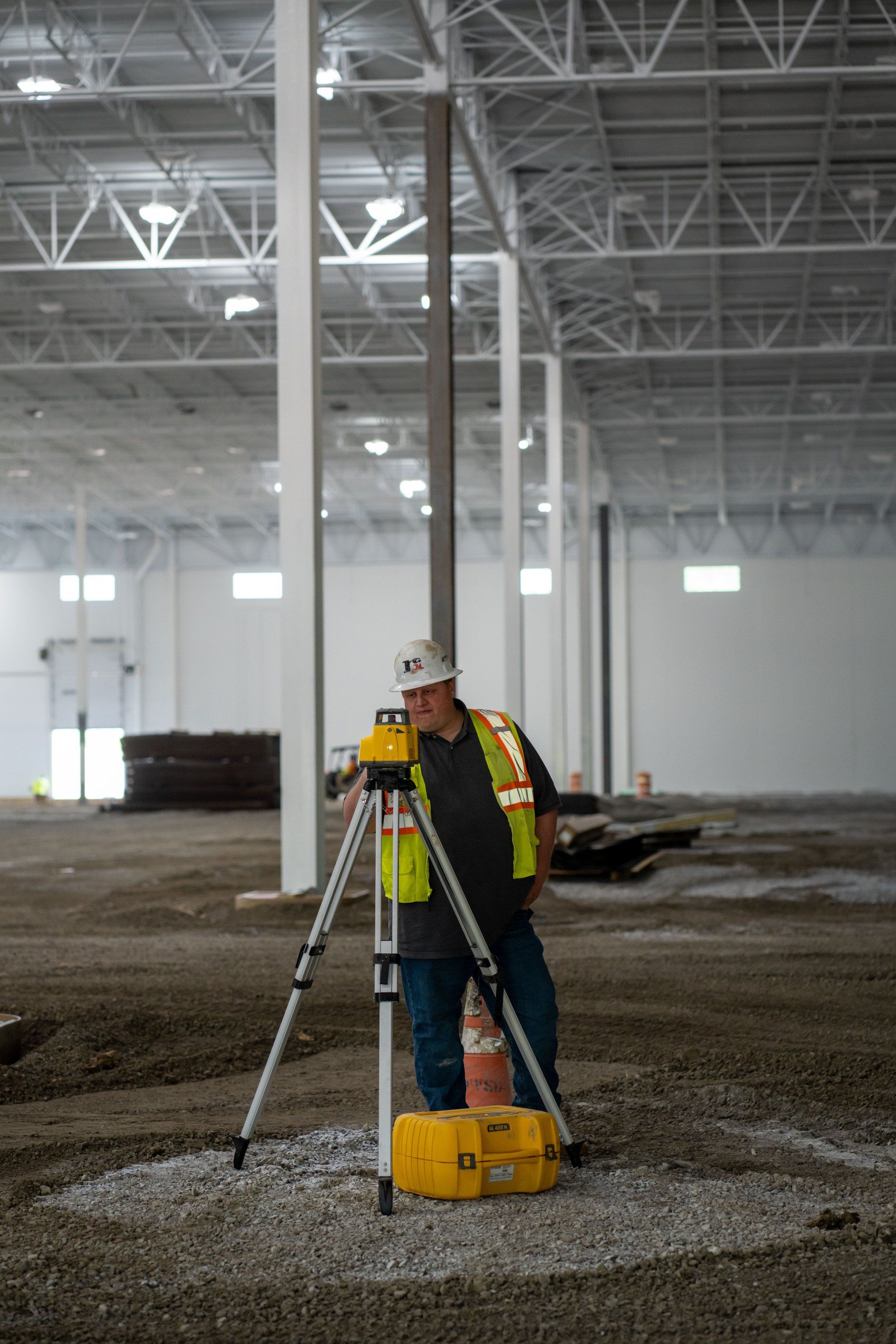 A construction worker is using a level in a large warehouse.