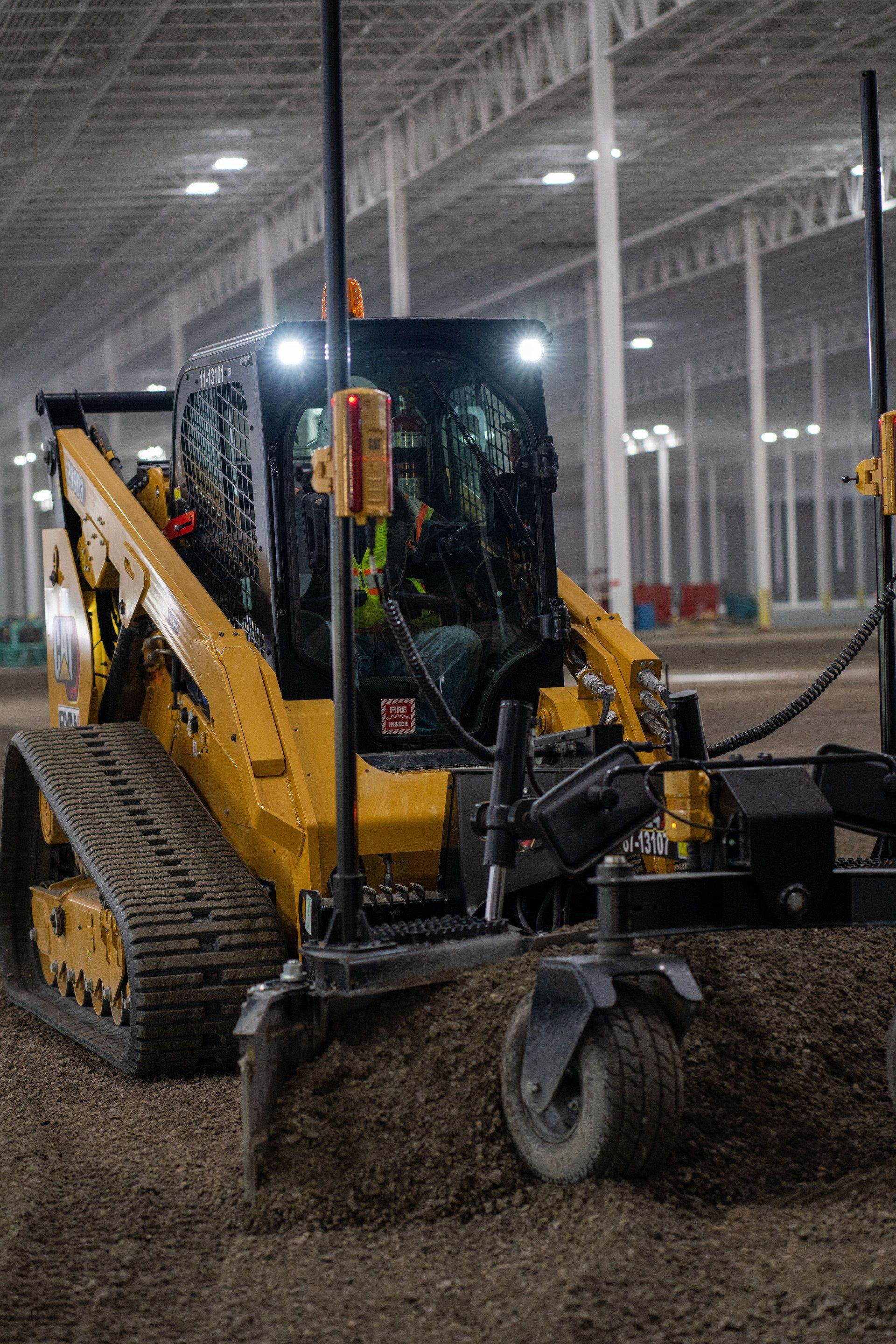A man is driving a bulldozer in a large warehouse.