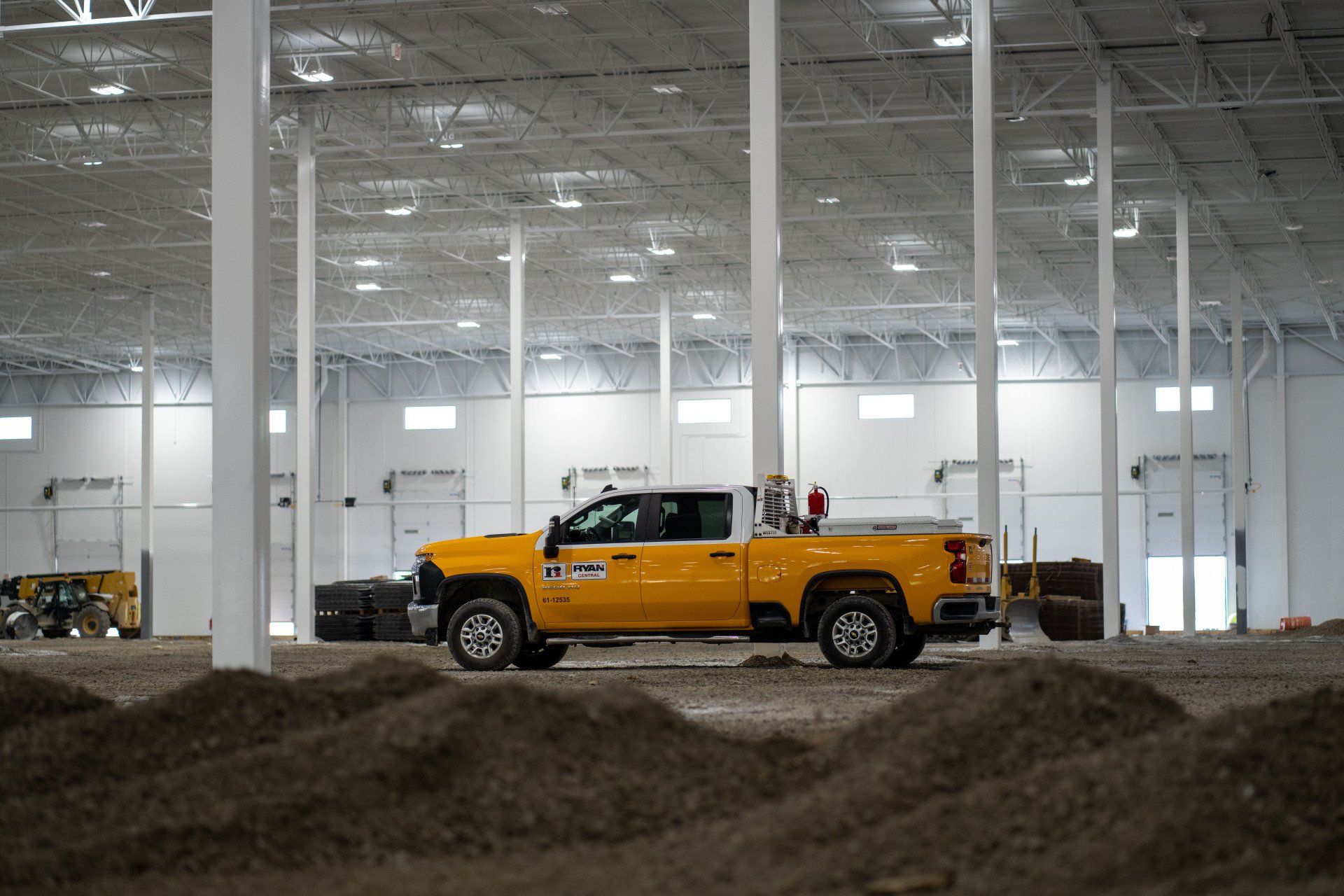 A yellow truck is parked in a large warehouse.
