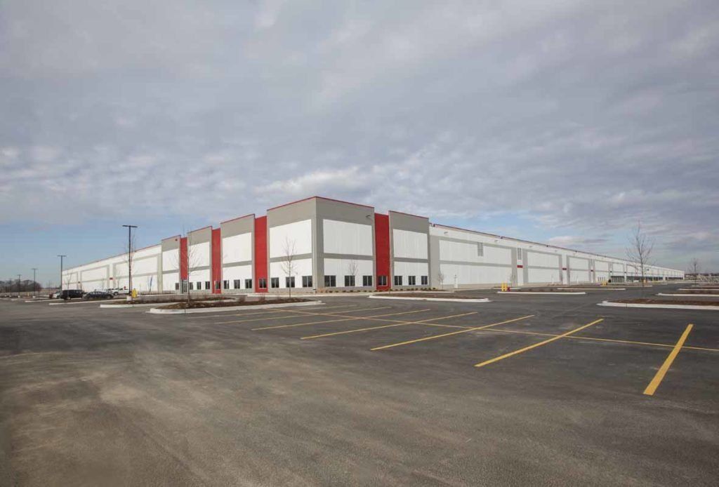 A large warehouse with a parking lot in front of it.