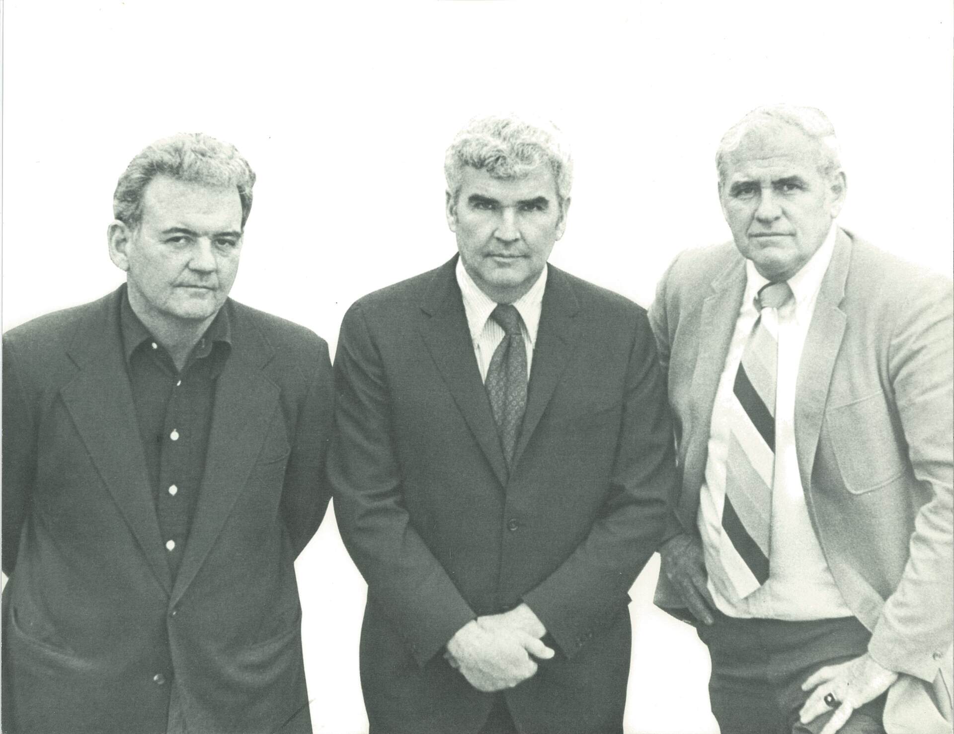 Three men in suits and ties pose for a photo