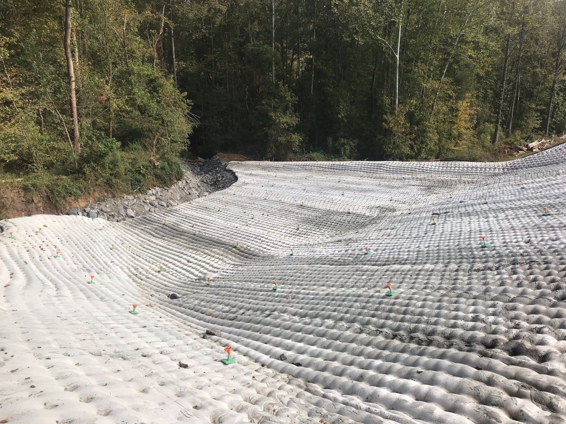 A large pile of dirt is sitting on top of a hill in the middle of a forest.
