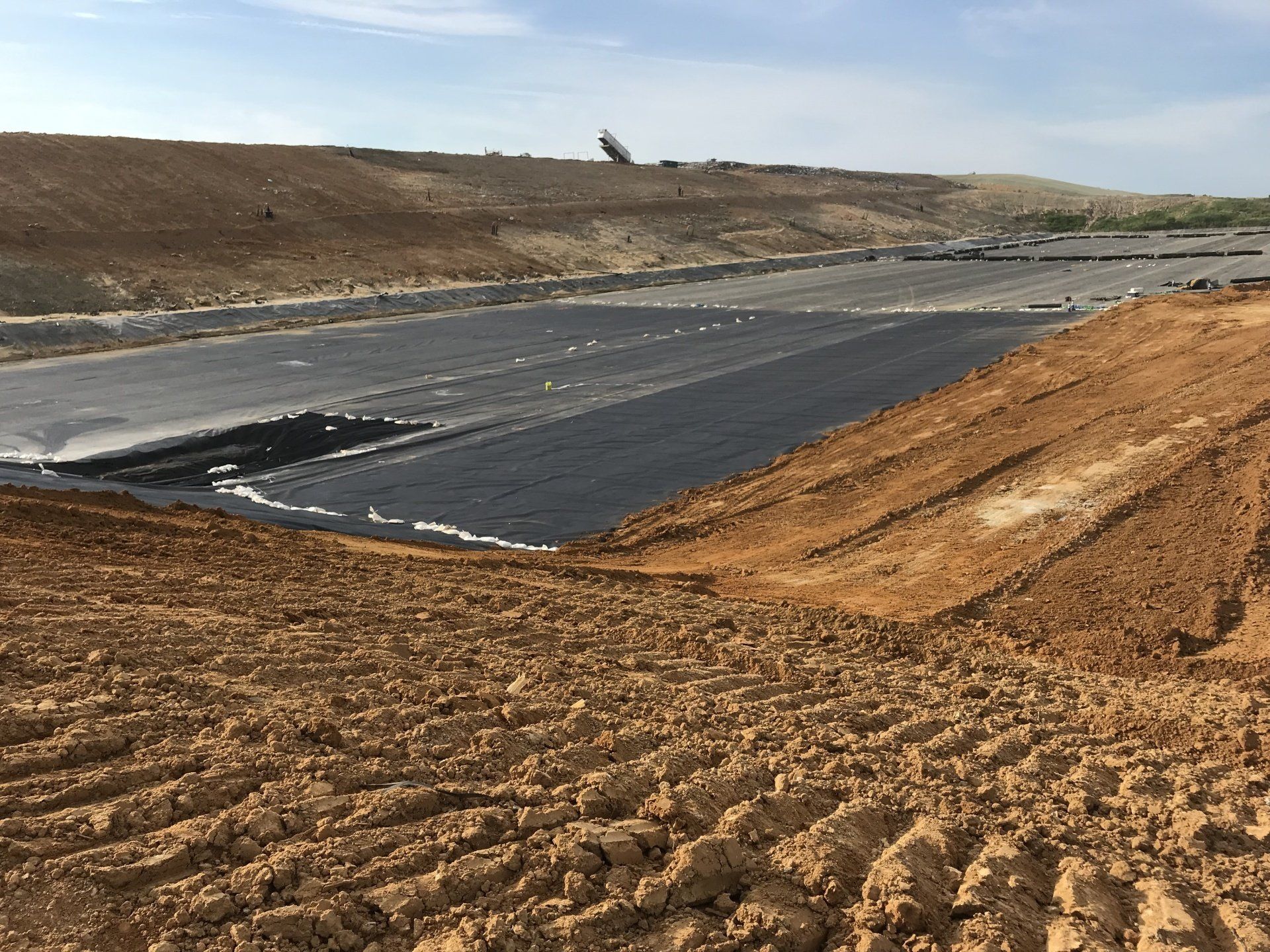 A large body of water is being built in the middle of a dirt field.