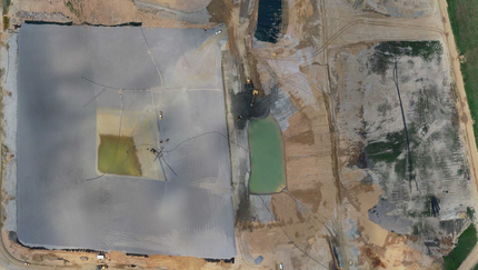 An aerial view of a large dirt field with a pond in the middle.