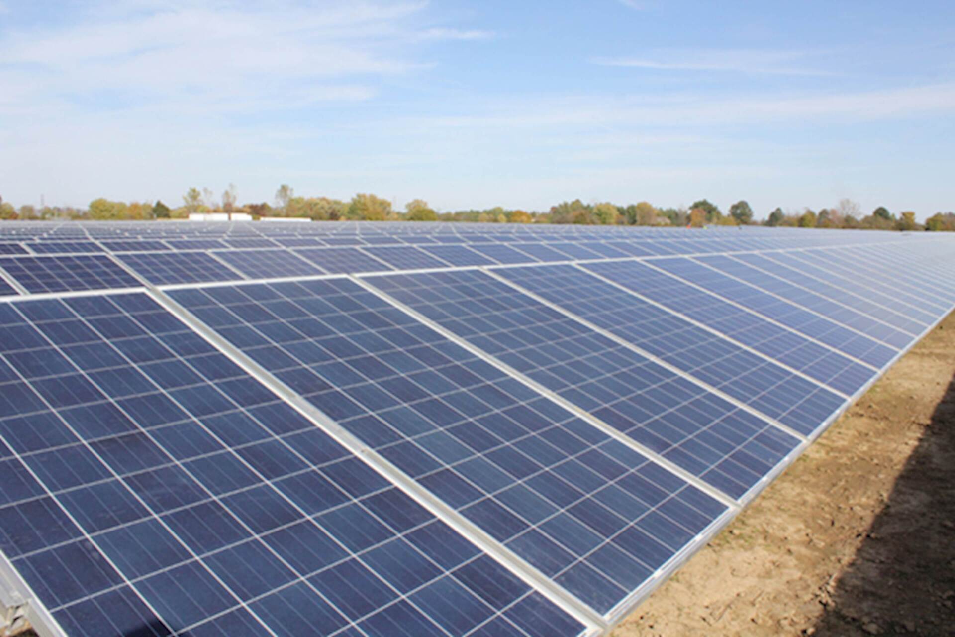 A field of solar panels with a blue sky in the background