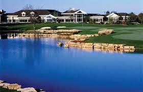 There is a large body of water in the foreground and a golf course in the background.
