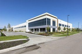 A large white building with a lot of windows is sitting next to a road.
