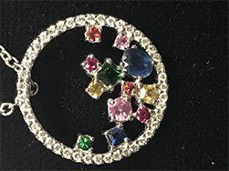 Silver pendant necklace with a circle of white gems, and colorful gems scattered inside.