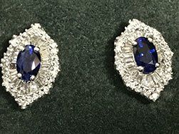 Pair of sapphire and diamond earrings on a dark green surface.