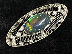 Oval Art Deco brooch with an opal center and diamond accents.