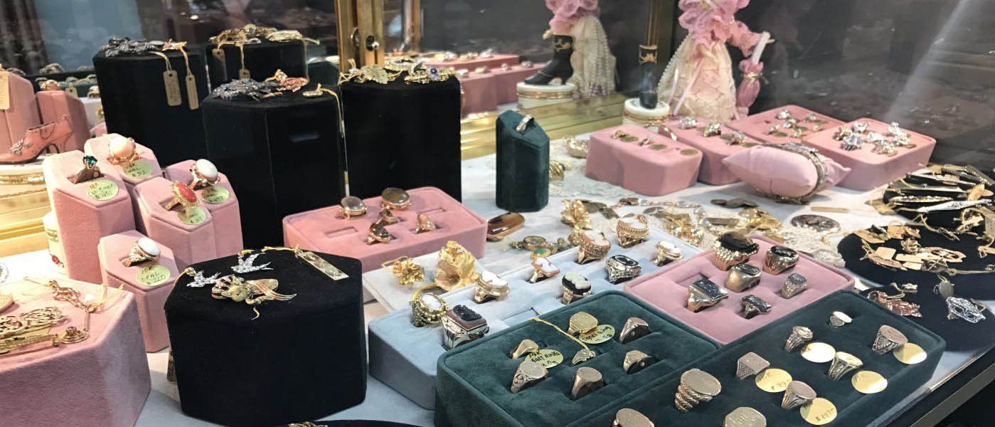 Jewelry display case with rings, earrings, and necklaces on velvet stands.