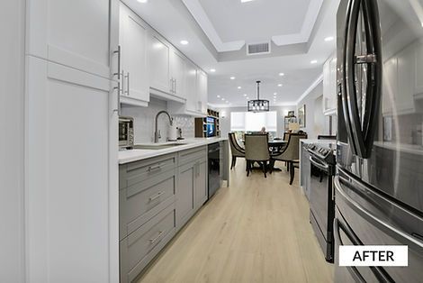 Modern kitchen with white and gray cabinets, stainless steel appliances, and wood flooring. Dining area visible in background