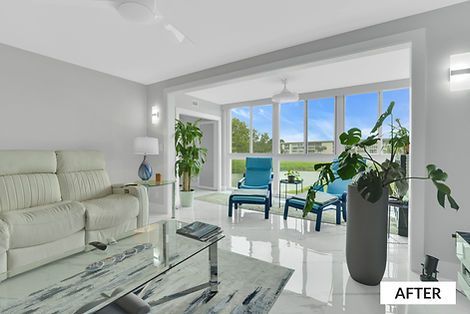 Living room with white walls, recliner, glass table, and seating area with blue chairs and large windows overlooking outdoors