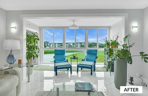 Bright living room with blue chairs facing large windows overlooking a lake and buildings