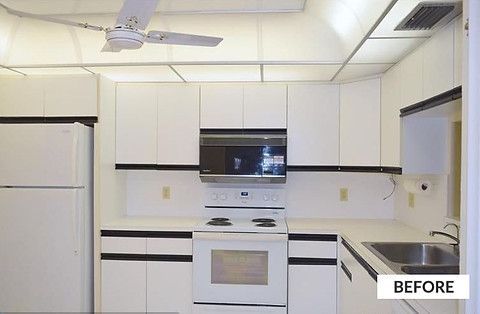 White kitchen with cabinets, refrigerator, stove, microwave, and sink; ceiling fan.