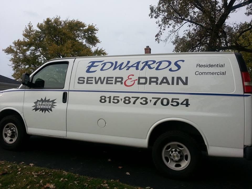 White Edwards Sewer & Drain service van parked outdoors with phone number 815-873-7054 visible