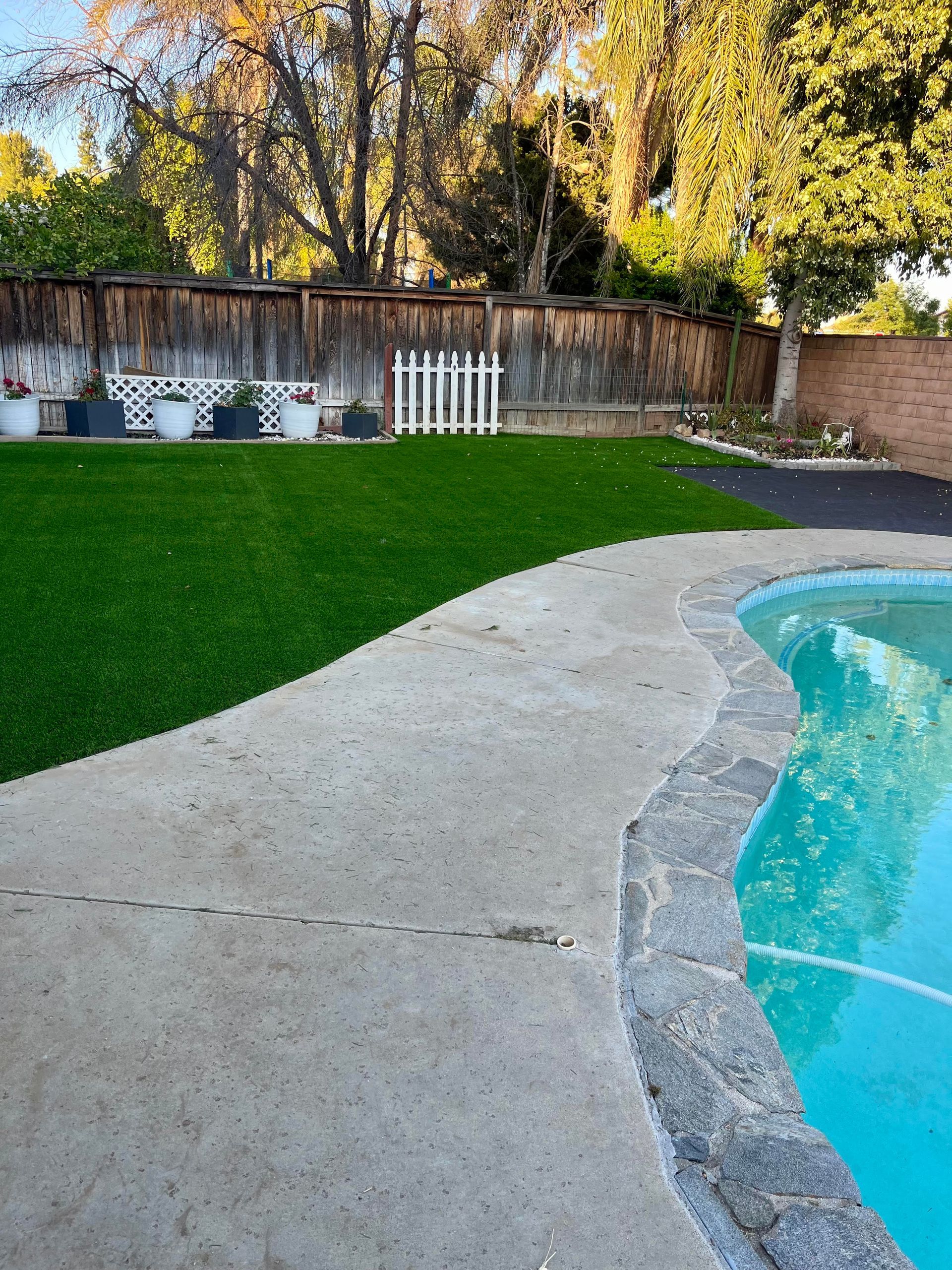 A backyard with a swimming pool and a fence