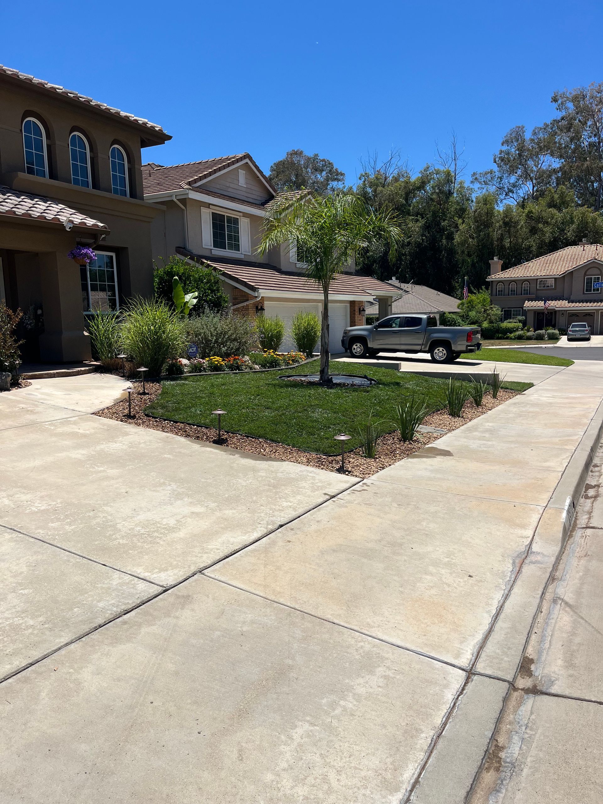 Residential driveway and front yard with a parked pickup truck on a sunny day