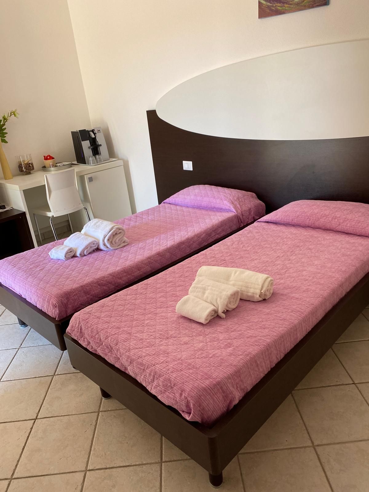 Letto a castello in legno con lenzuola blu a fantasia, contro una parete bianca con decorazioni floreali blu.