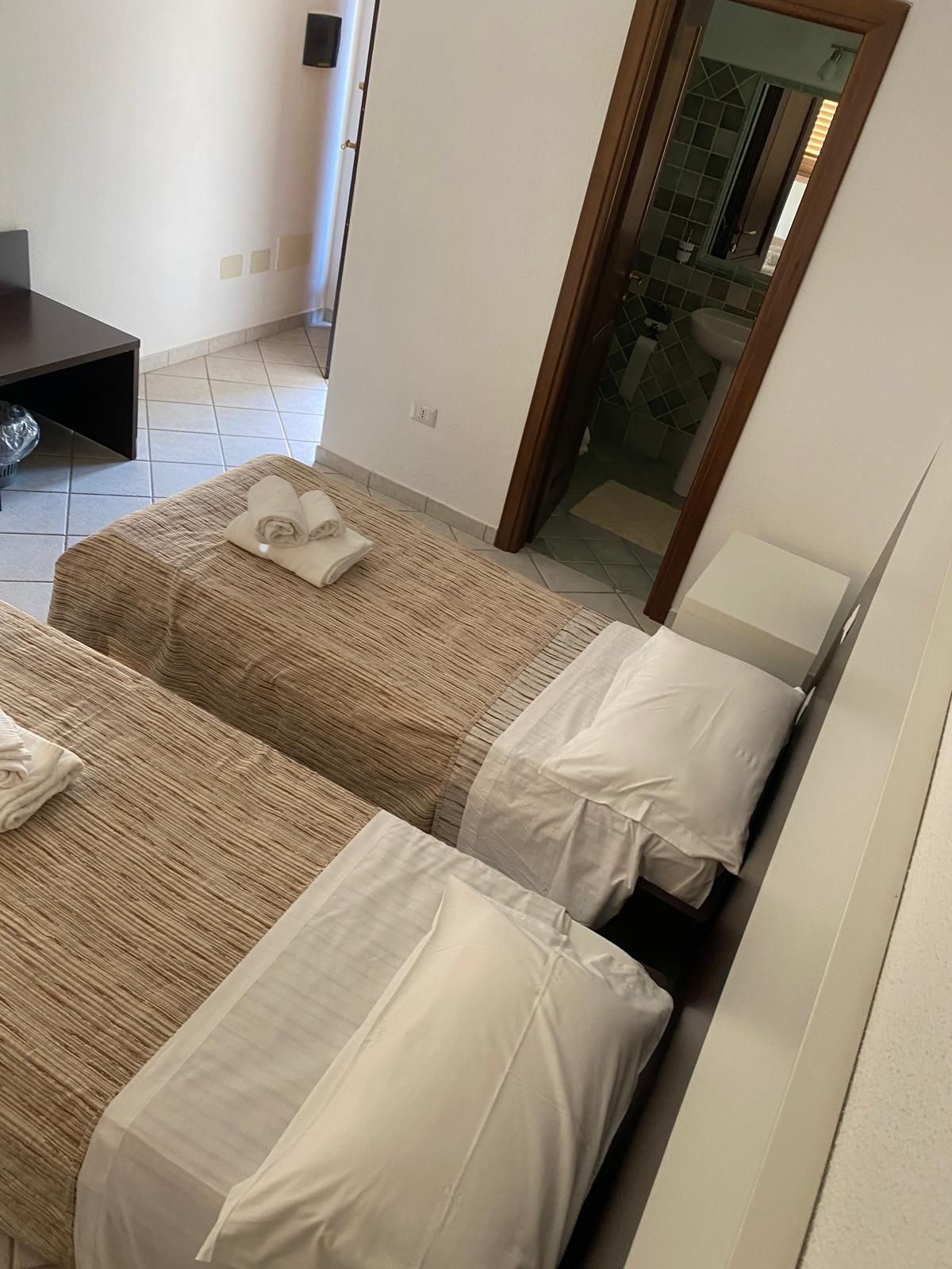 Una camera da letto essenziale con due letti singoli, copriletti a fantasia e un armadio in legno.