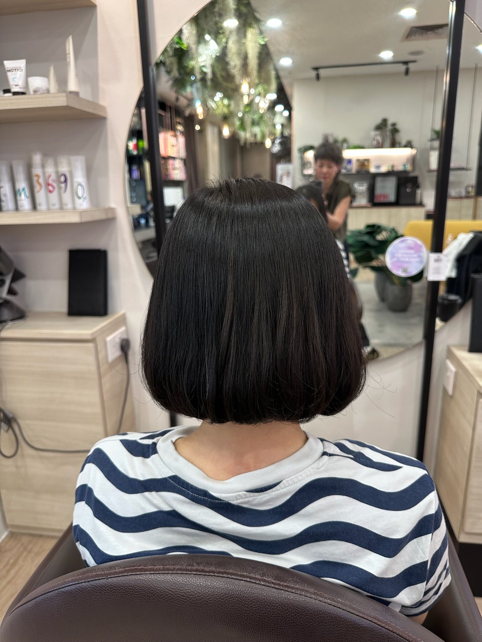 Back view of a sleek, chin-length black bob with ends curved inwards in a C-curl, styled by Jefernie at Kimage Salon Singapore