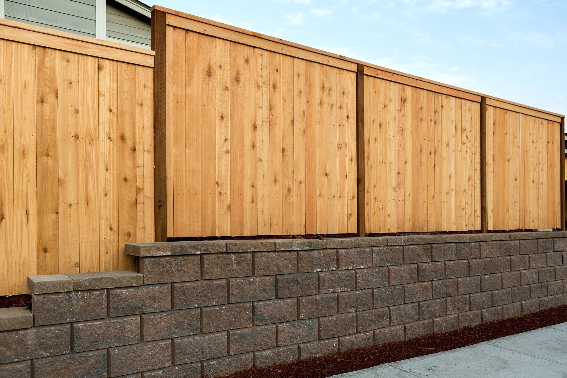 Wooden fence atop a brown retaining wall