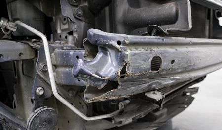 Damaged blue car bumper showing impact damage and metal structure.