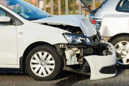 A white car showing significant front-end damage after colliding with the rear of a silver vehicle.