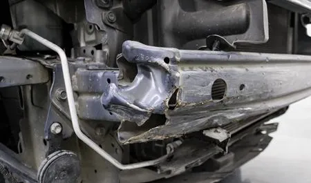 Severely damaged metal motorcycle frame and body panel after a crash, close-up view