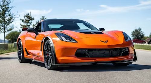 Orange Corvette sports car parked outdoors on a sunny day, front view