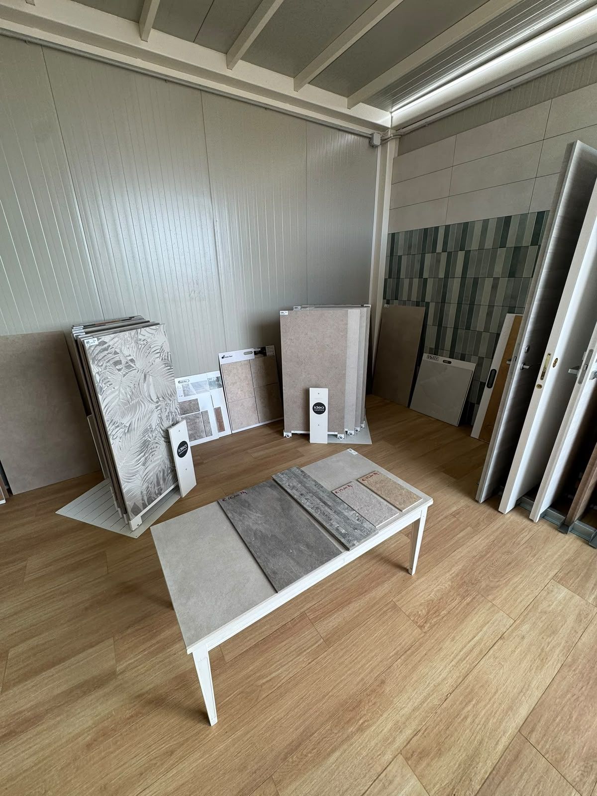 Esposizione di piastrelle in showroom con campionari, un tavolino e pannelli di pavimentazione appoggiati alla parete