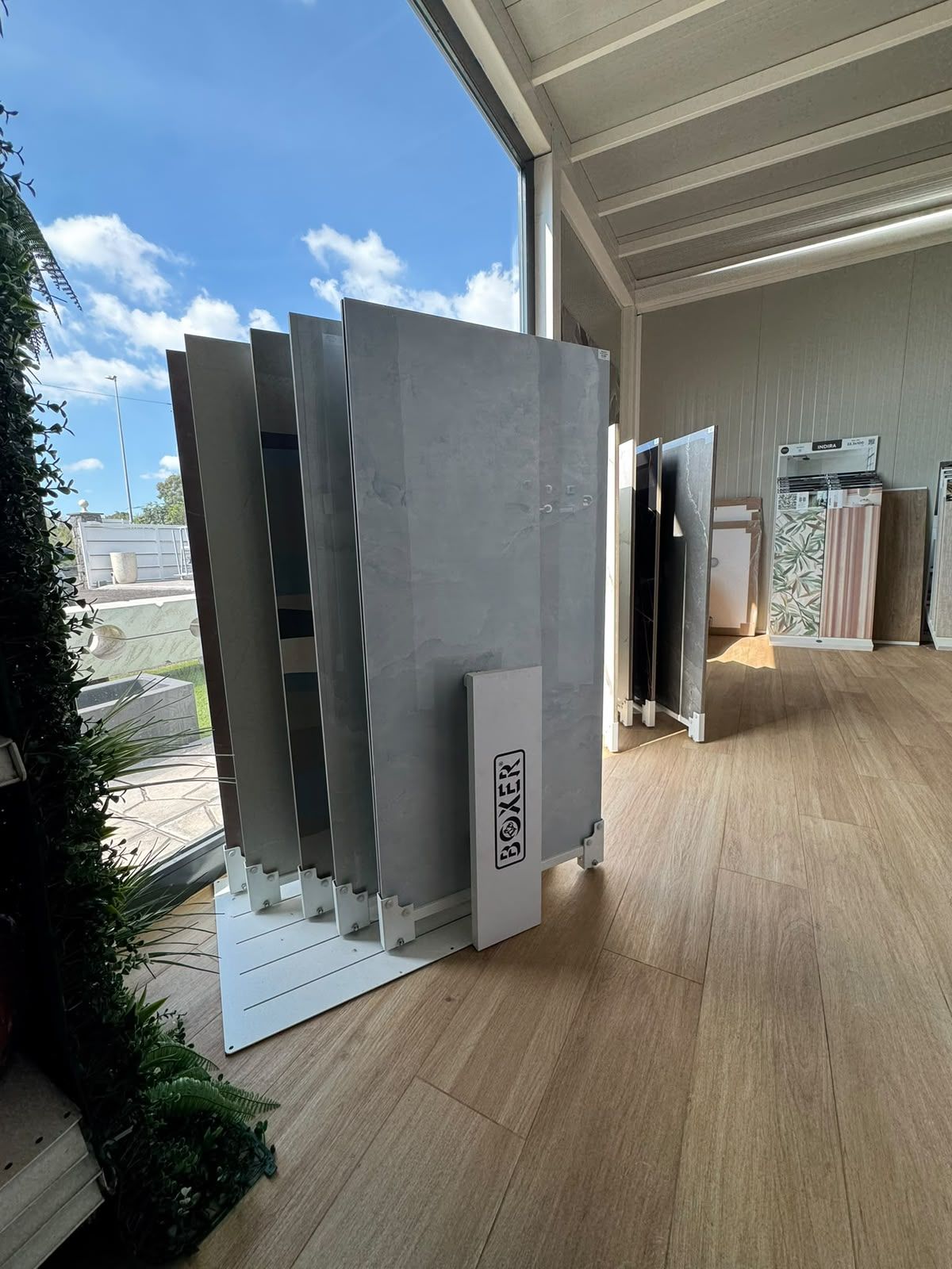 Esposizione di grandi pannelli grigi e campioni di legno in uno showroom luminoso con pavimento in legno