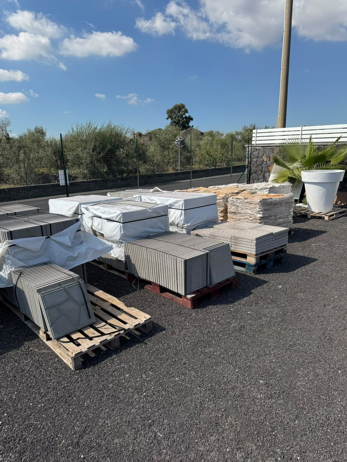 Pile di materiali da costruzione bianchi su pallet, su un tetto sotto un cielo azzurro