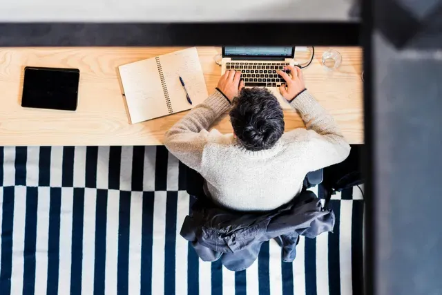 A man is sitting at a desk using a laptop computer.