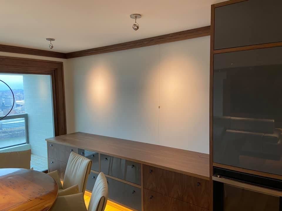 Empty room with built-in desk, chair, large window, and warm wood trim