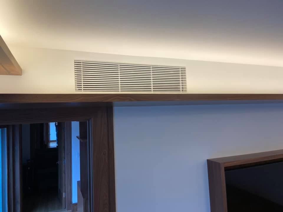 Indoor scene with a wall vent above a doorway and part of a wall-mounted TV on the right