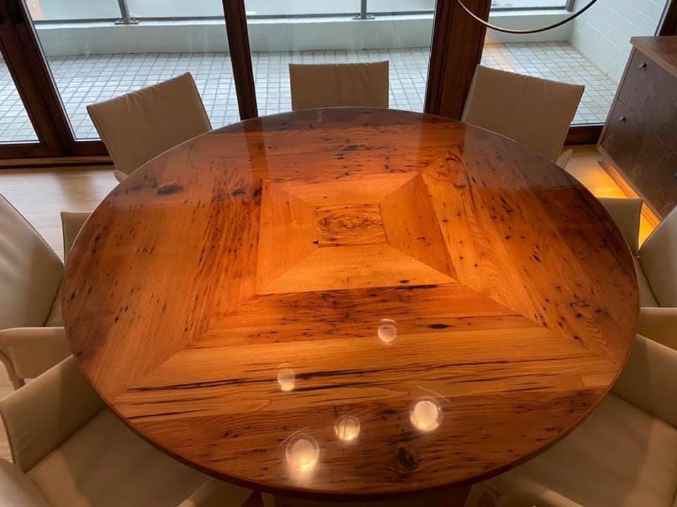 Round wooden dining table with four beige chairs in a bright room
