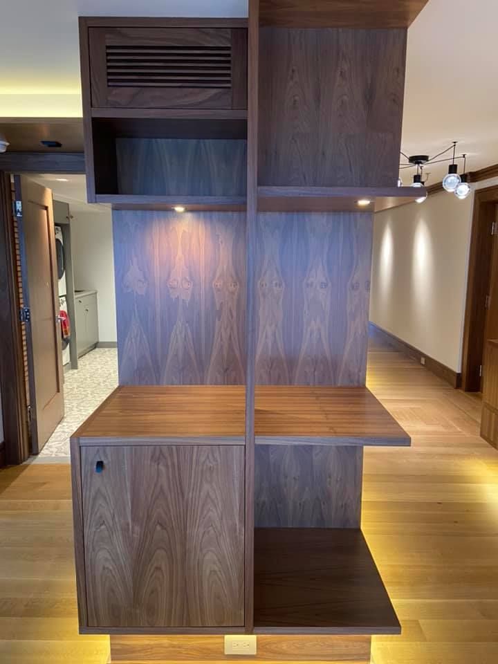 Wooden built-in shelving and cabinet unit in a hallway, with dark wood panels and open compartments.